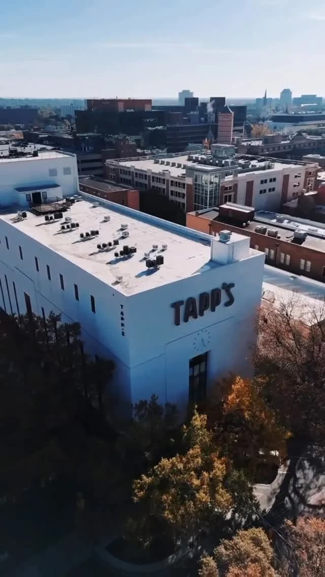 The Tapp's building from above — the TAPP'S lettering on the white facade, with the clock face on the corner below it, and downtown Columbia behind